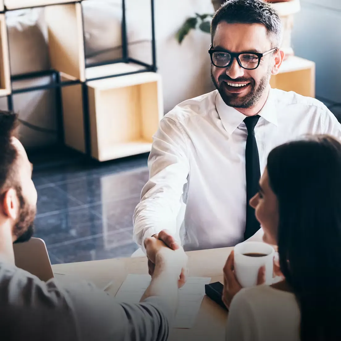 two men shaking their hands ans a woman taking a coffe