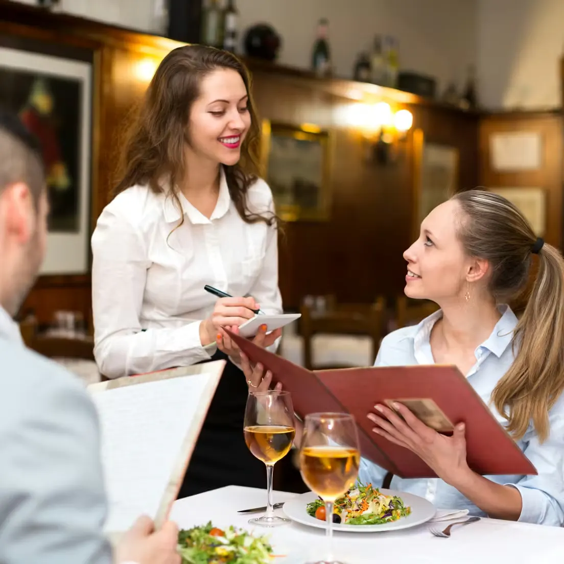 a woman with a menu talking with a waitress