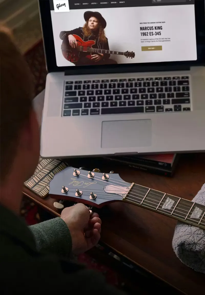 retail experience at Gibson.com on a laptop with a hand holding a guitar