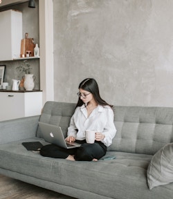a woman working on her computer with a cup of coffee in her hand