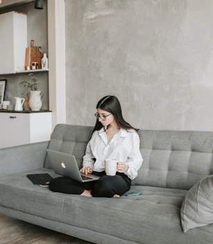 a woman working on her computer with a cup of coffee in her hand