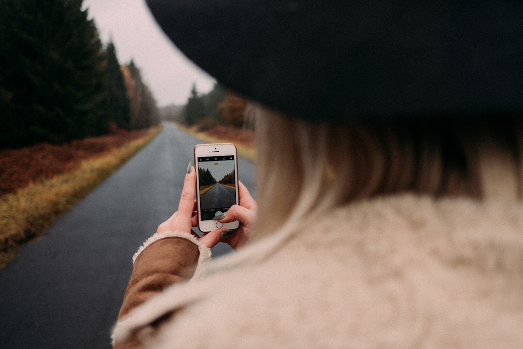 a girl with a hat takes a picture of a landscape