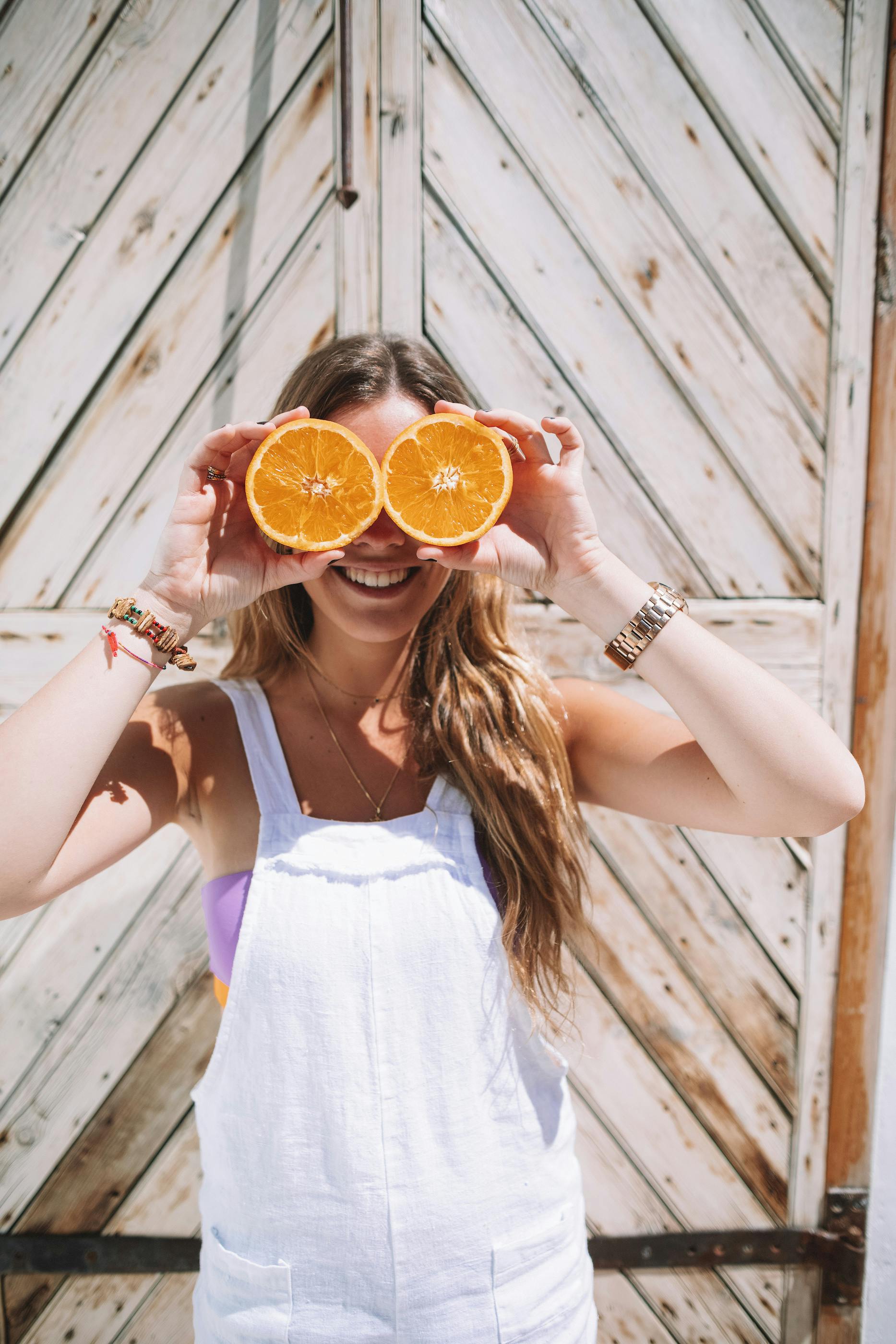 girl holding oranges in front of her eyes