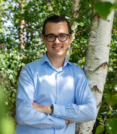 Giel staat in het bos en kijkt lachend in de camera