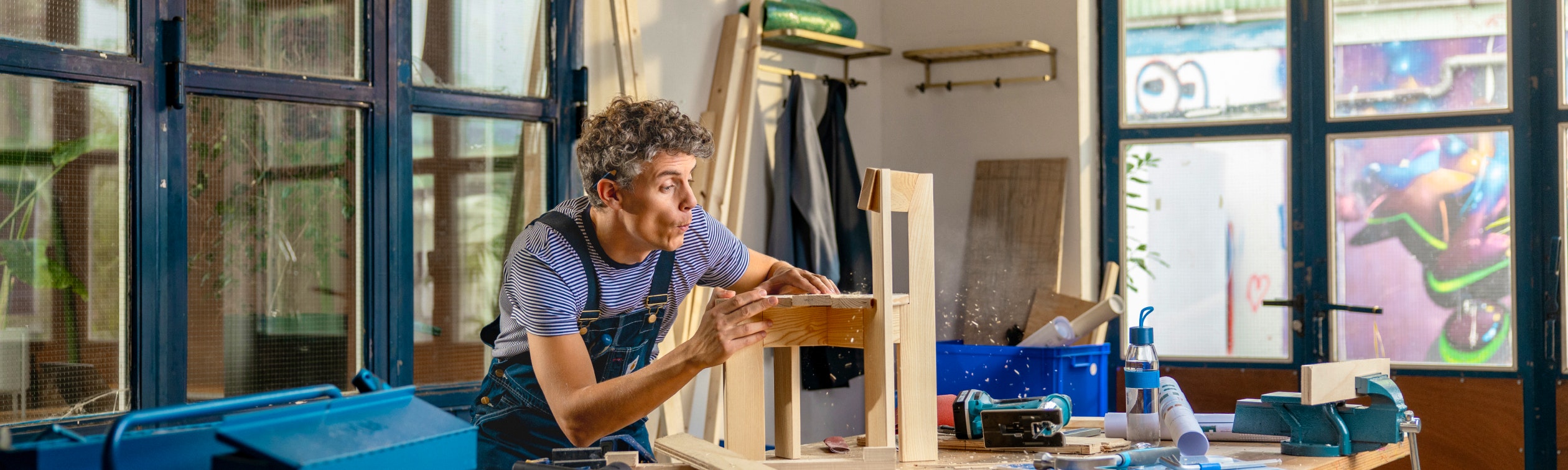 Timmerman blaast stof van een kinderstoeltje