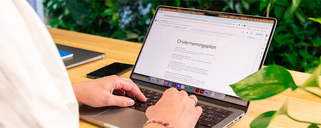 Iemand achter laptop schrijft ondernemingsplan