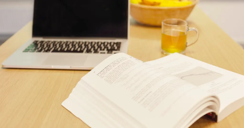 Een laptop en opengeslagen boek