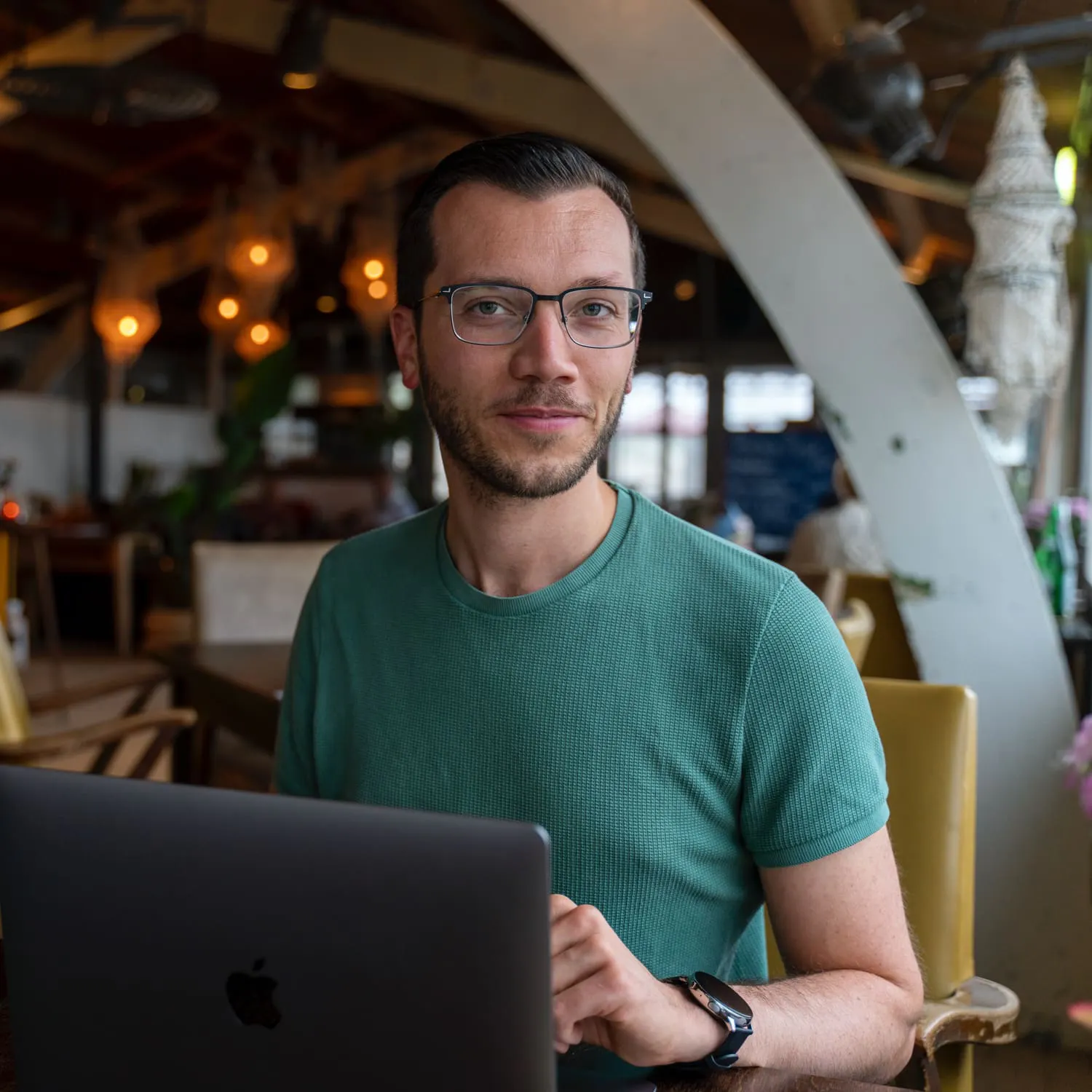 Simon kijkt vanachter zijn laptop in de camera