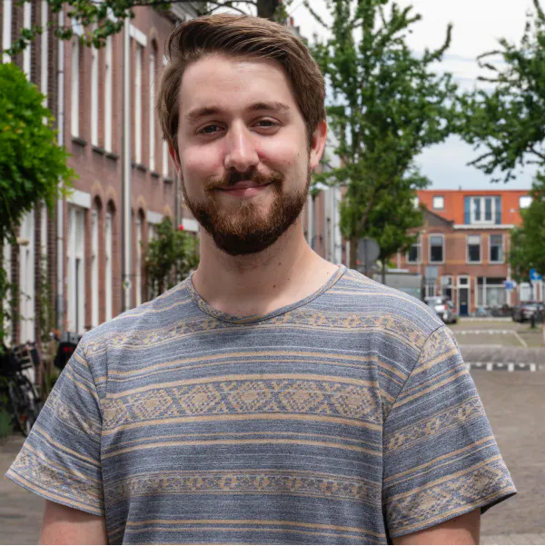Jasper staat op straat en lacht in de camera