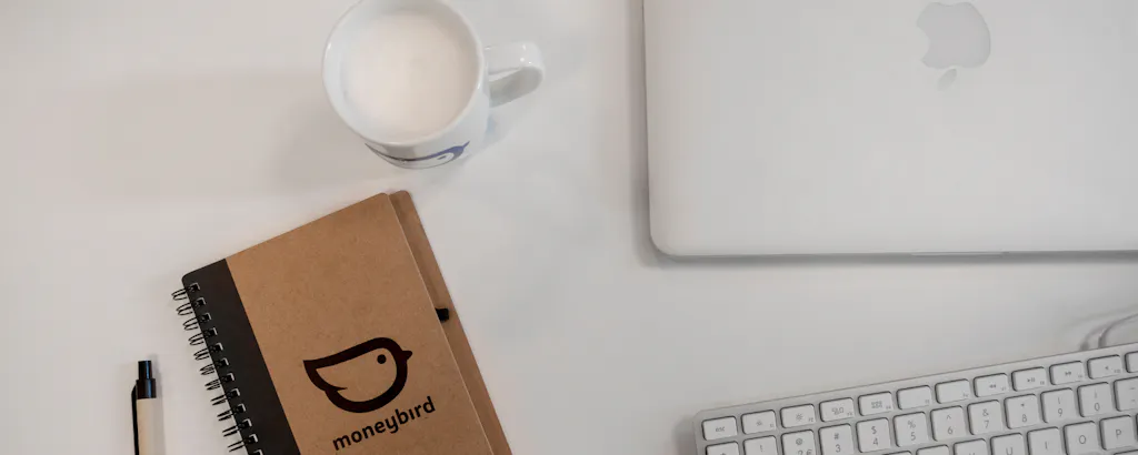 Een bureau met schrijfboekje, kopje en laptop
