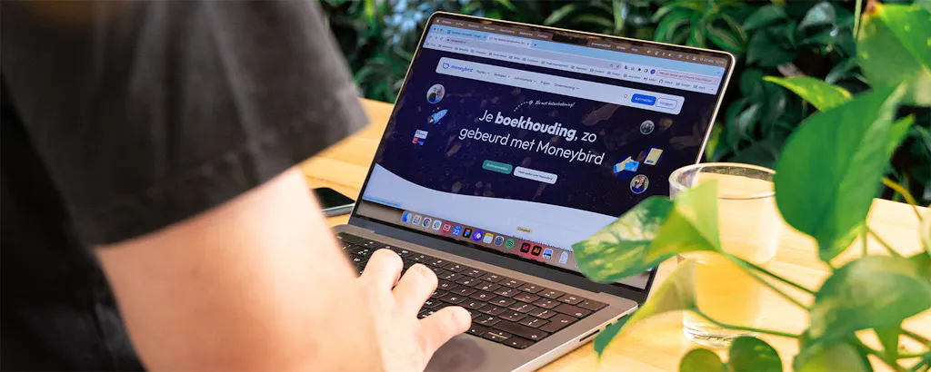 Persoon achter de laptop bekijkt Moneybird website