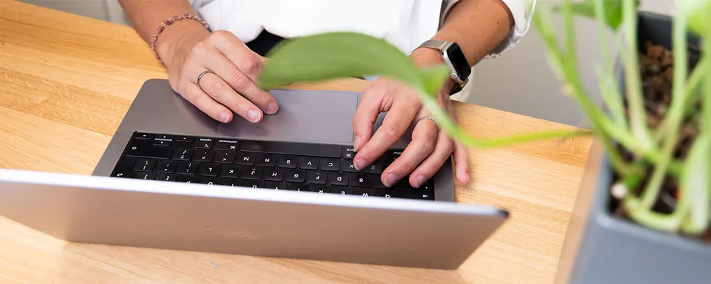 Handen die aan het typen zijn op laptop van boven gefotografeerd