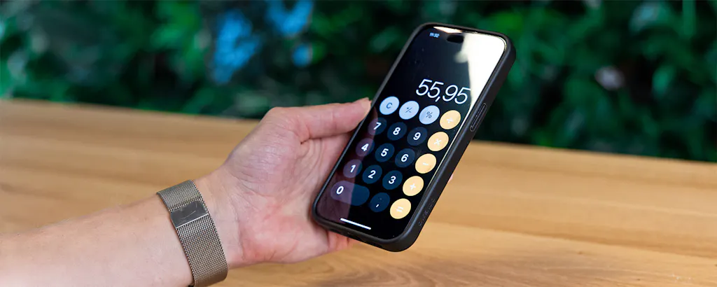 Close up van hand met telefoon waarop de rekenmachine wordt gebruikt