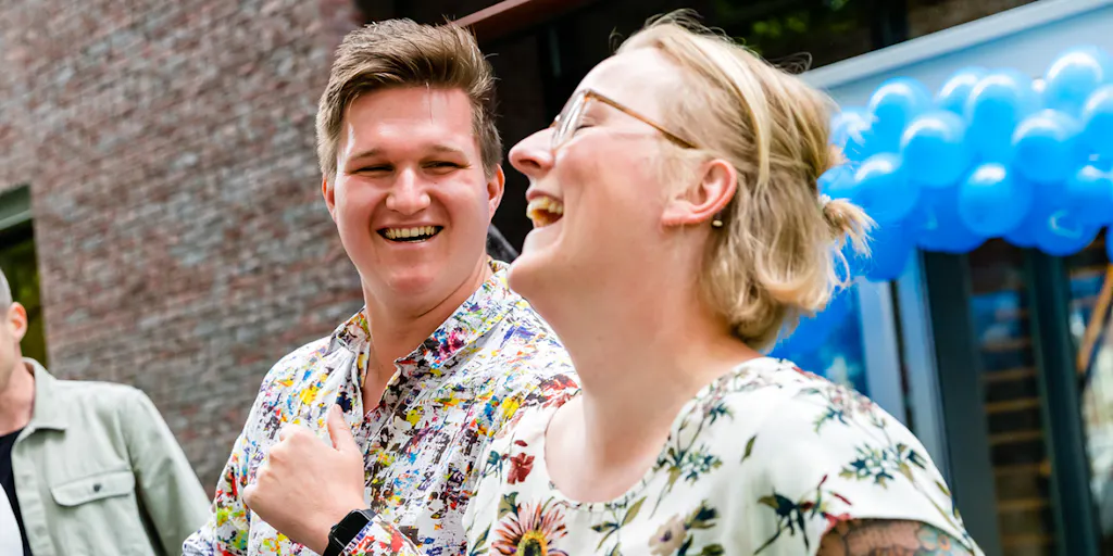 Twee collega's die met elkaar lachen op ons Great Place to Work feest in april 2022