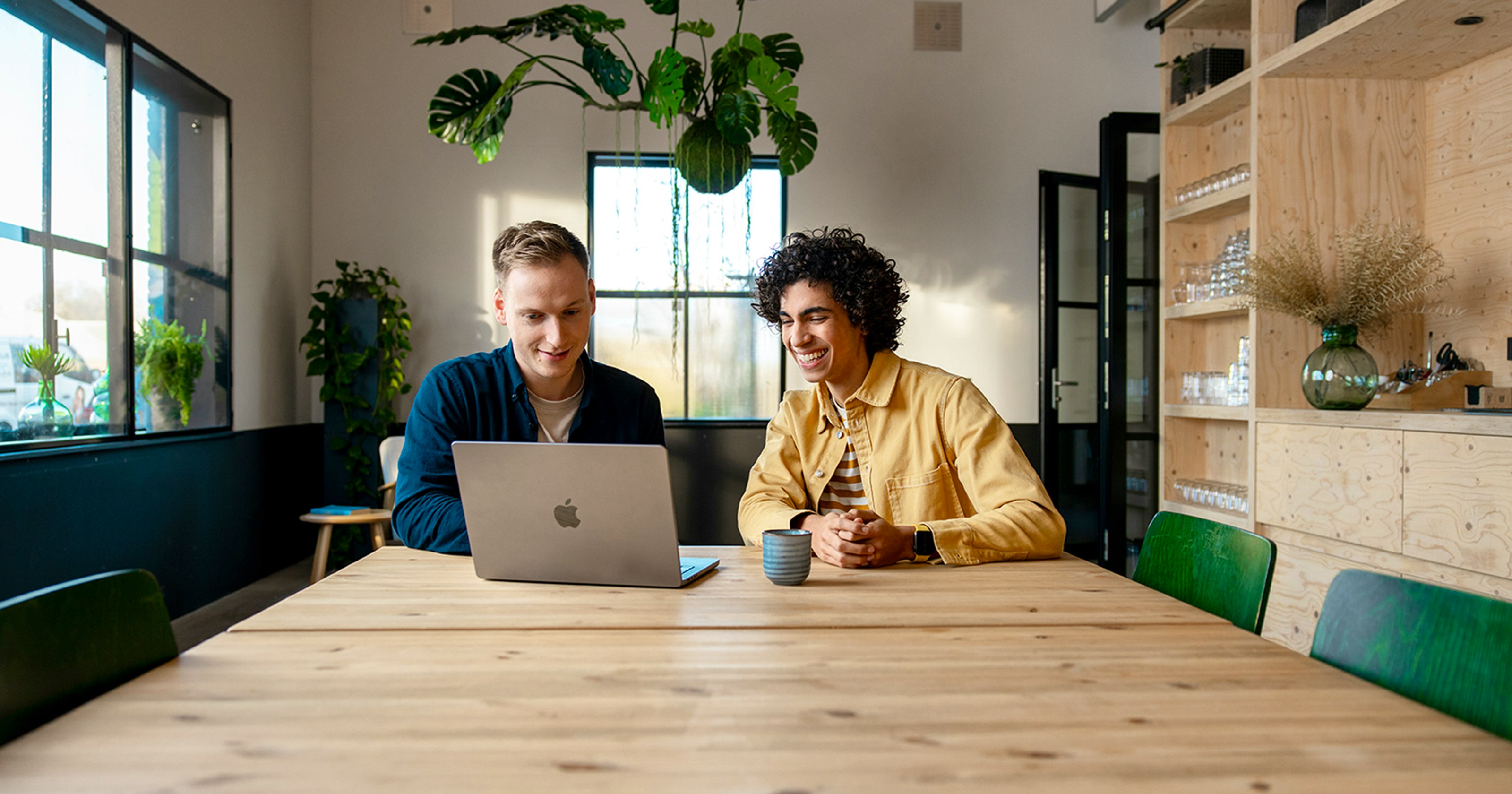 Twee ondernemers zijn het werk op een coworking plek. De ene ondernemer is op het werk aan haar laptop.