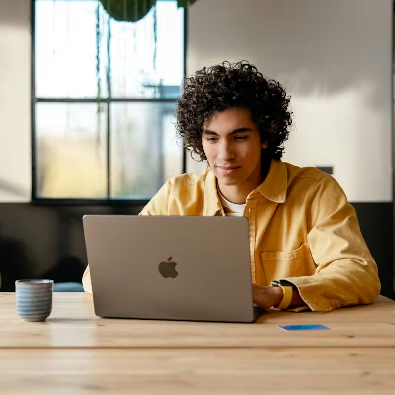 Ondernemer werkt aan tafel achter laptop met koffie en Moneybird betaalpas