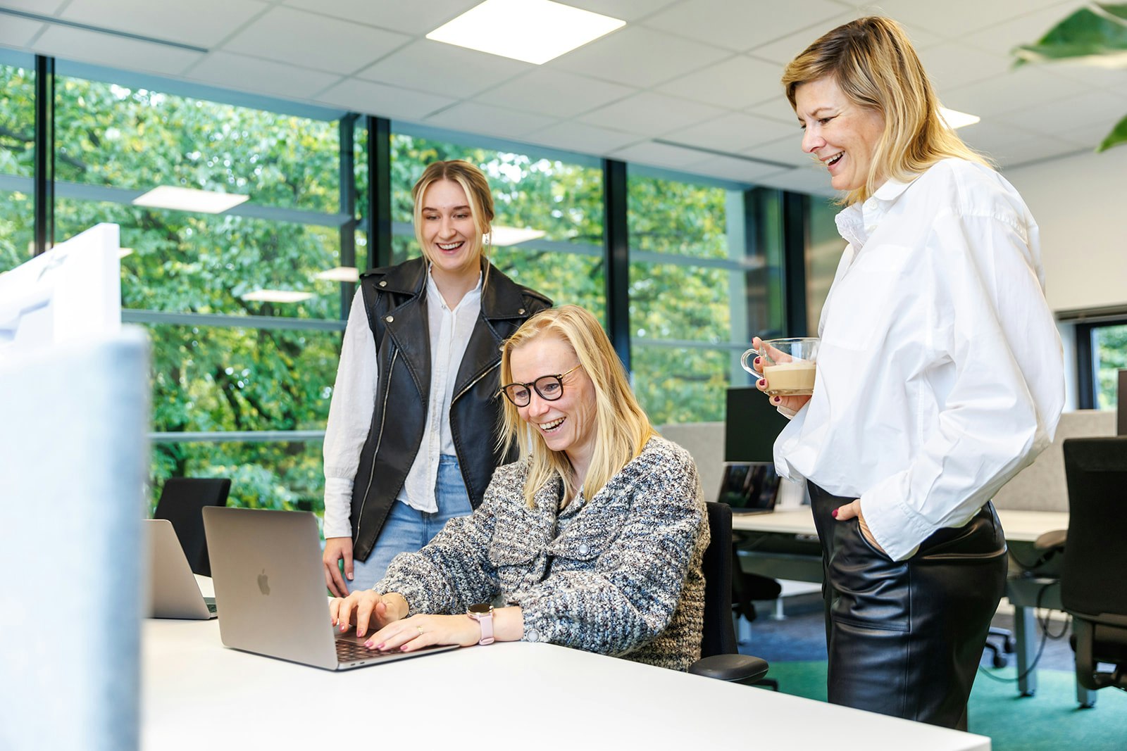 Drie collega'a lachend aan een bureau