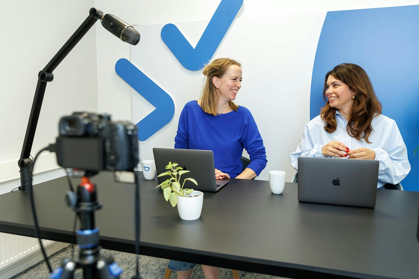 Liesbeth en Gladys tijdens livesessie achter bureau voor camera