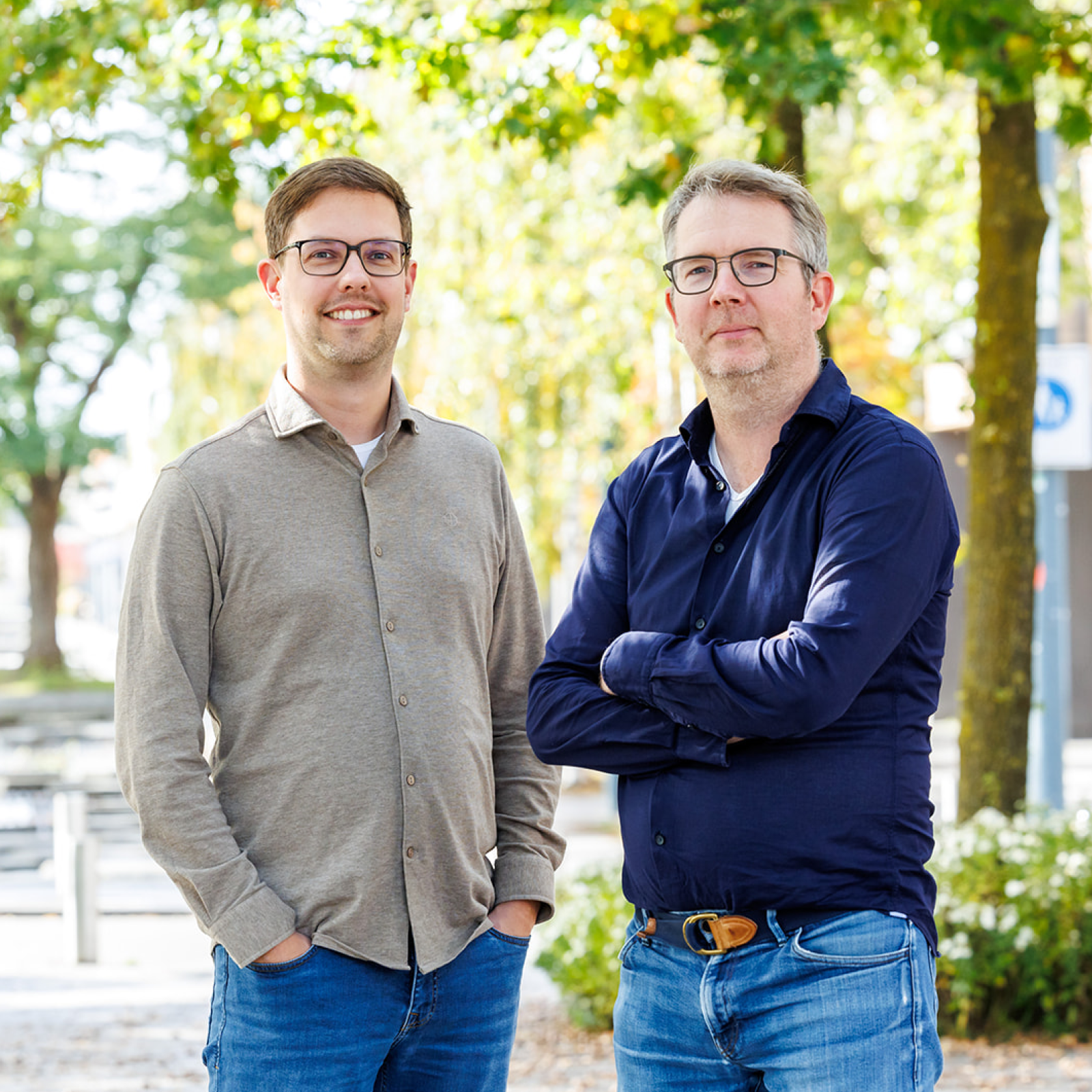 Edwin en Joost poseren buiten met groene bomen op de achtergrond