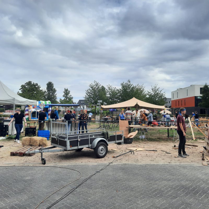 Collega's bouwen als teambuilding een festival op naast het pand van Moneybird met hout, partytenten, hooibalen en andere materialen.