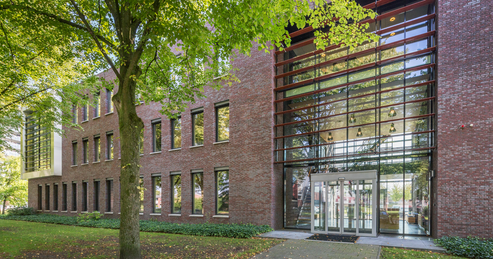 De voorkant van het Moneybird pand, 2 verdiepingen hoog, entree met schuifdeuren en veel glas.