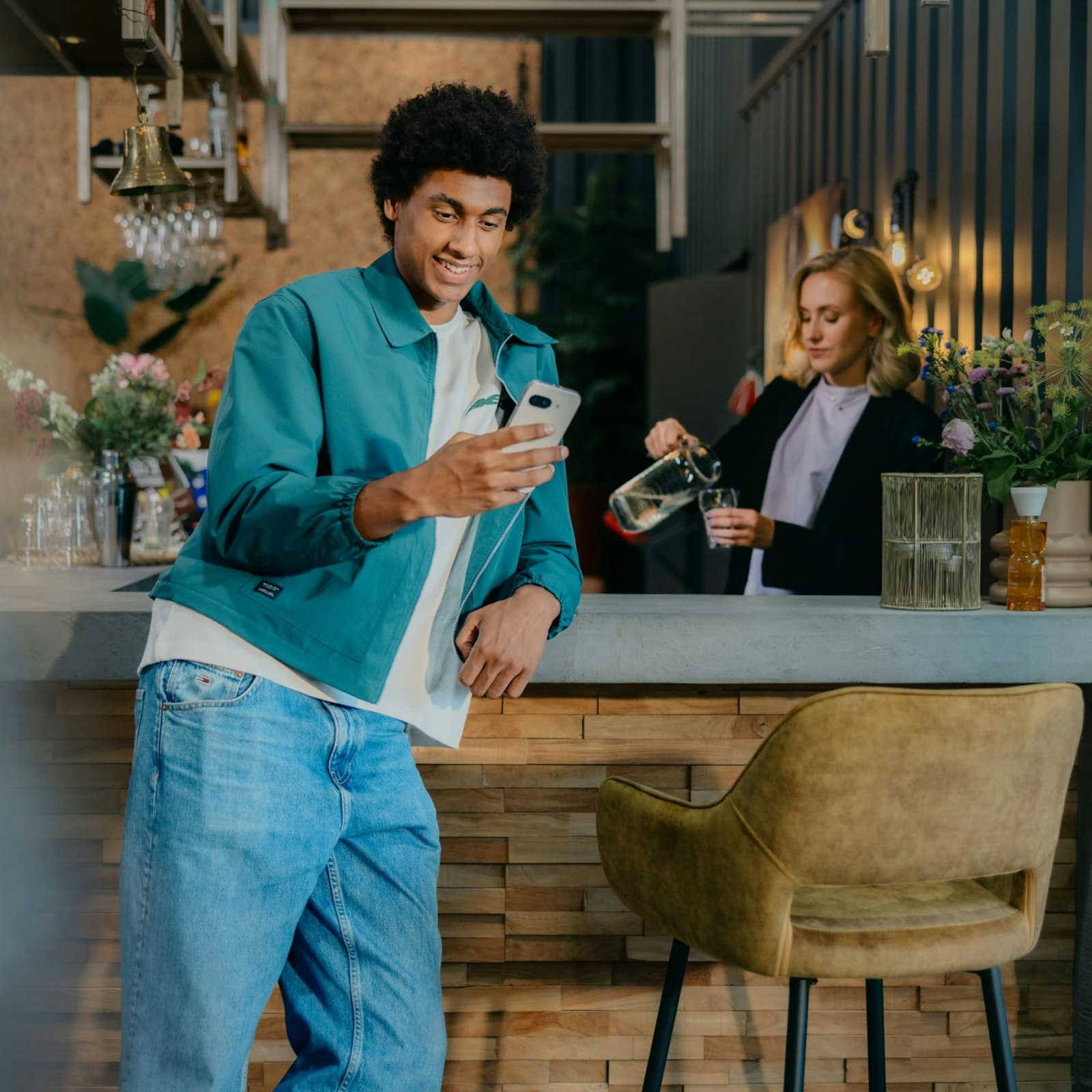 Matthieu staat aan de bar met zijn telefoon in zijn hand