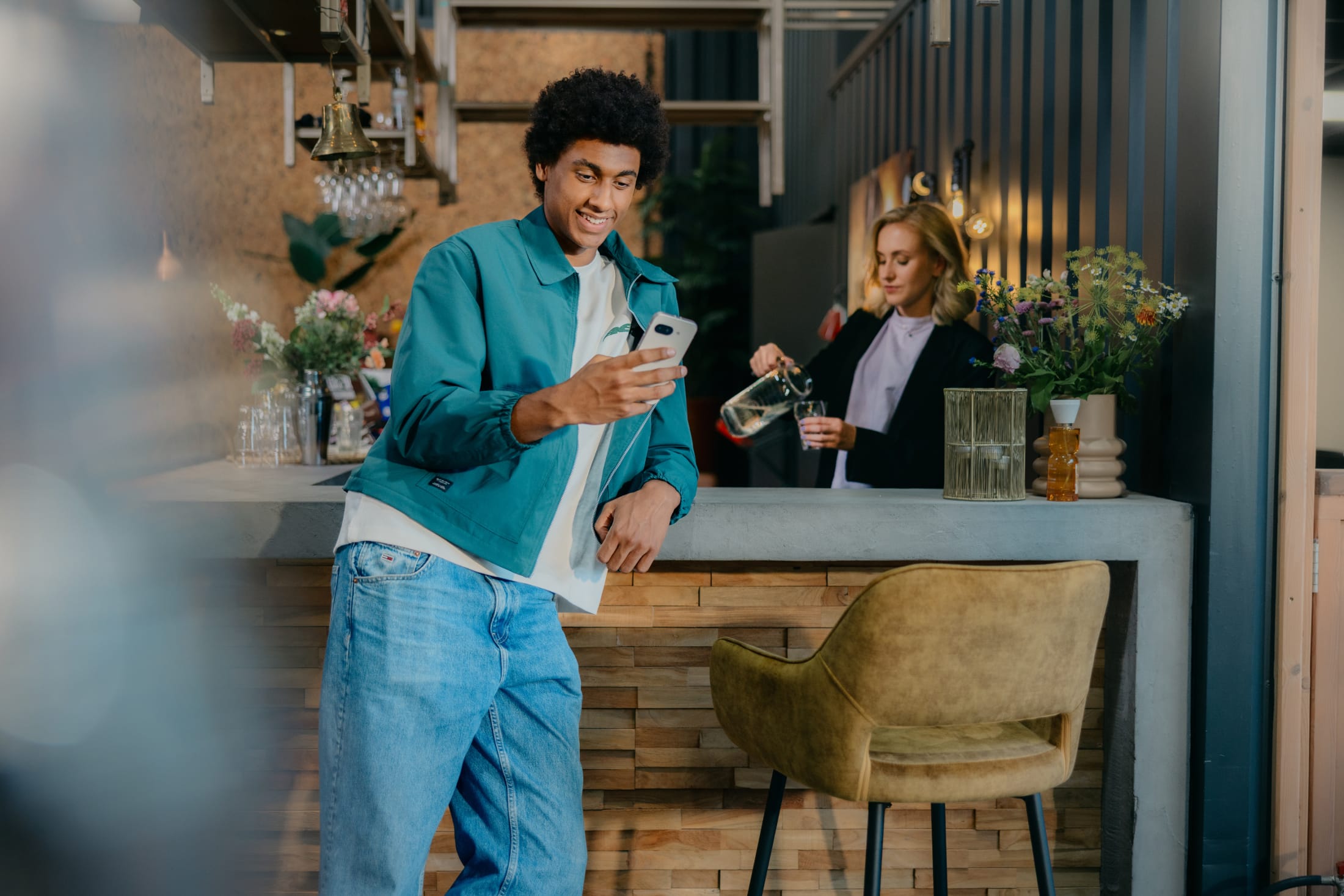Matthieu staat aan de bar en kijkt op zijn telefoon