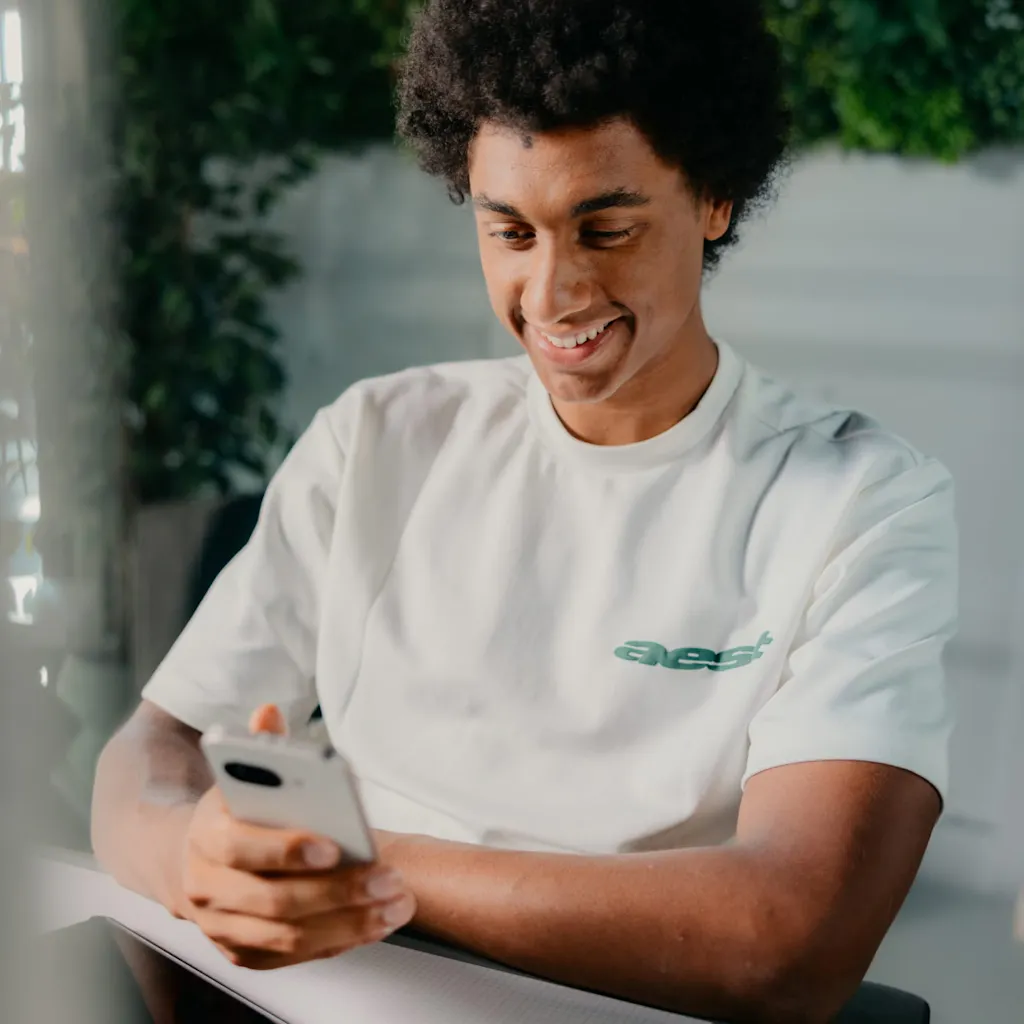 Matthieu zit achter zijn laptop met zijn telefoon in zijn hand
