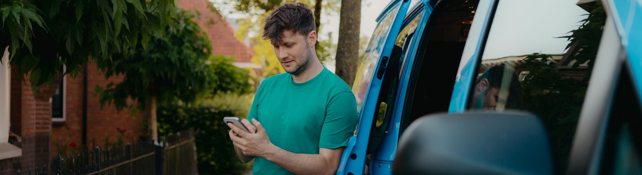 Arend met telefoon naast zijn werkbus