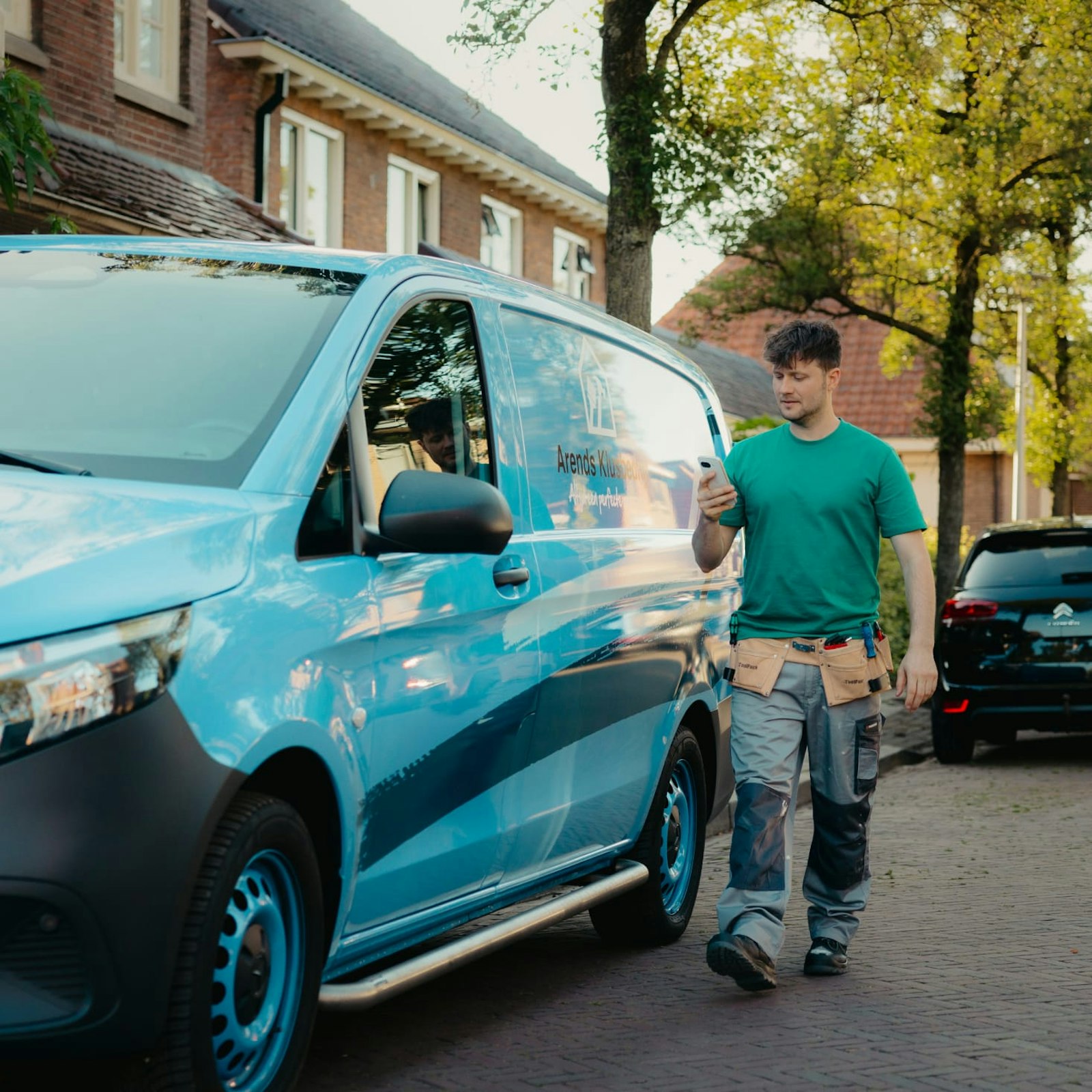 Arend met telefoon naast werkbus