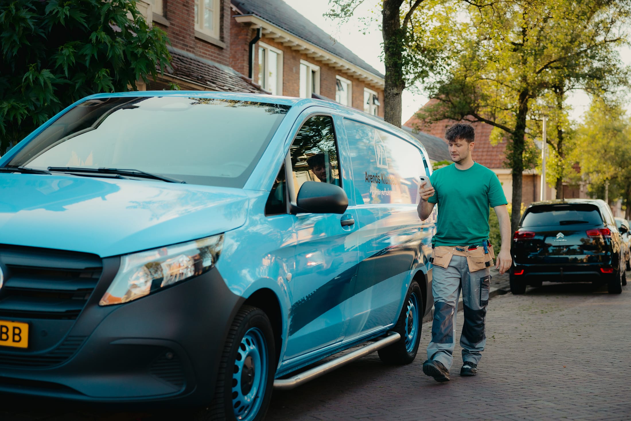 Arend met telefoon en zijn werkbus op de achtergrond
