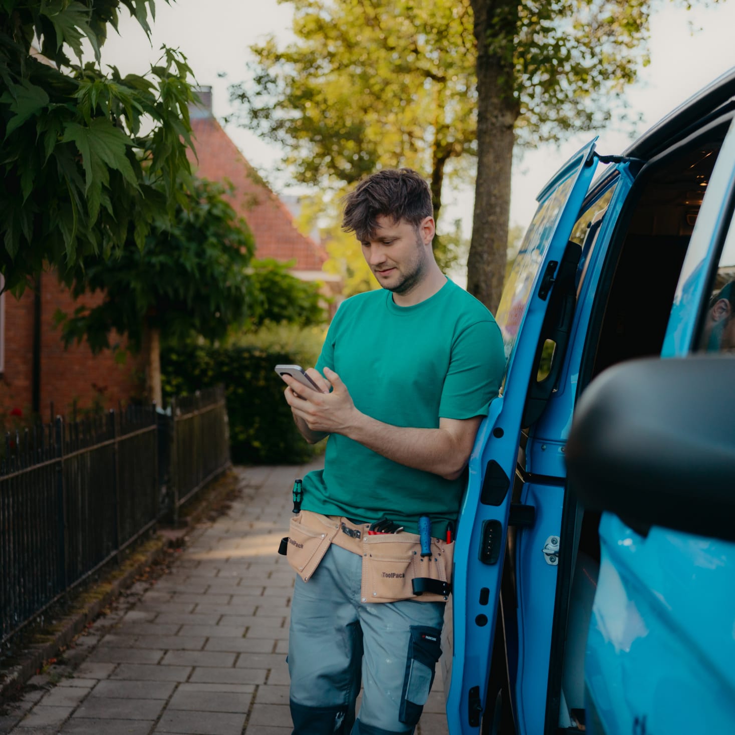 Arend staat bij zijn bus met zijn mobiel