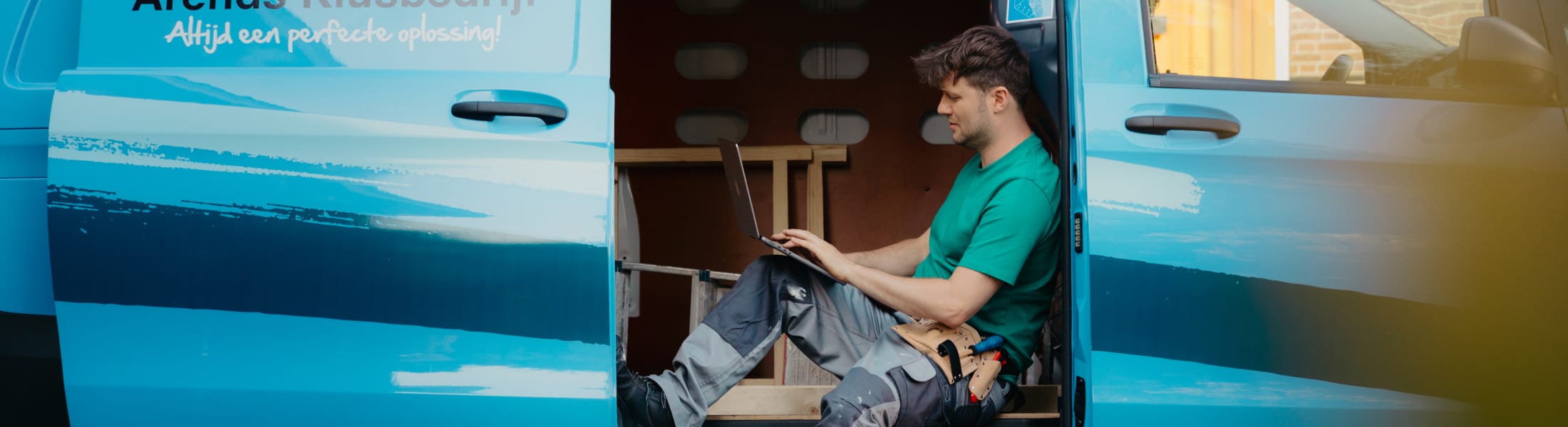 Arend met laptop in zijn werkbus met schuifdeur open