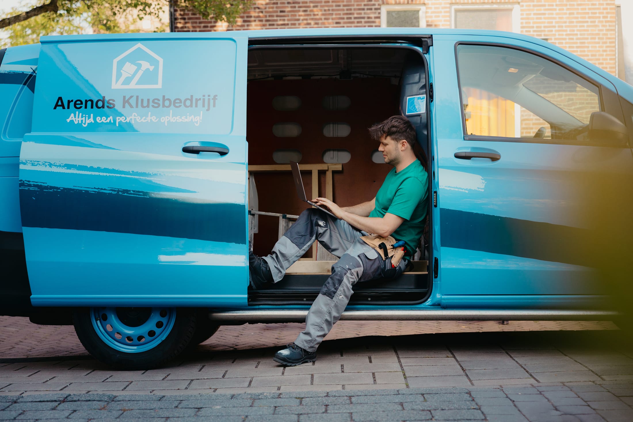 Arend in zijn werkbus achter de laptop met de deur open