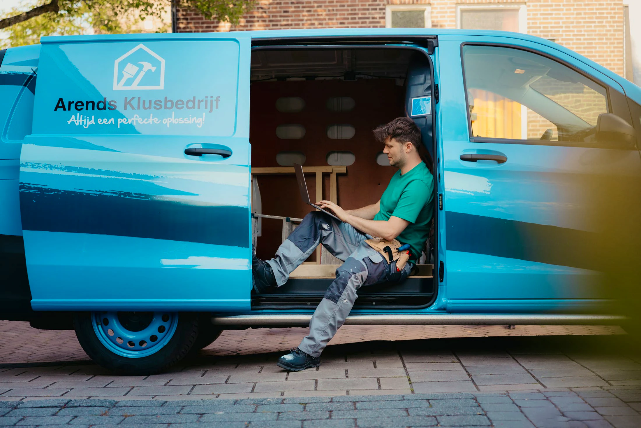 Arend in zijn werkbus achter de laptop met de deur open