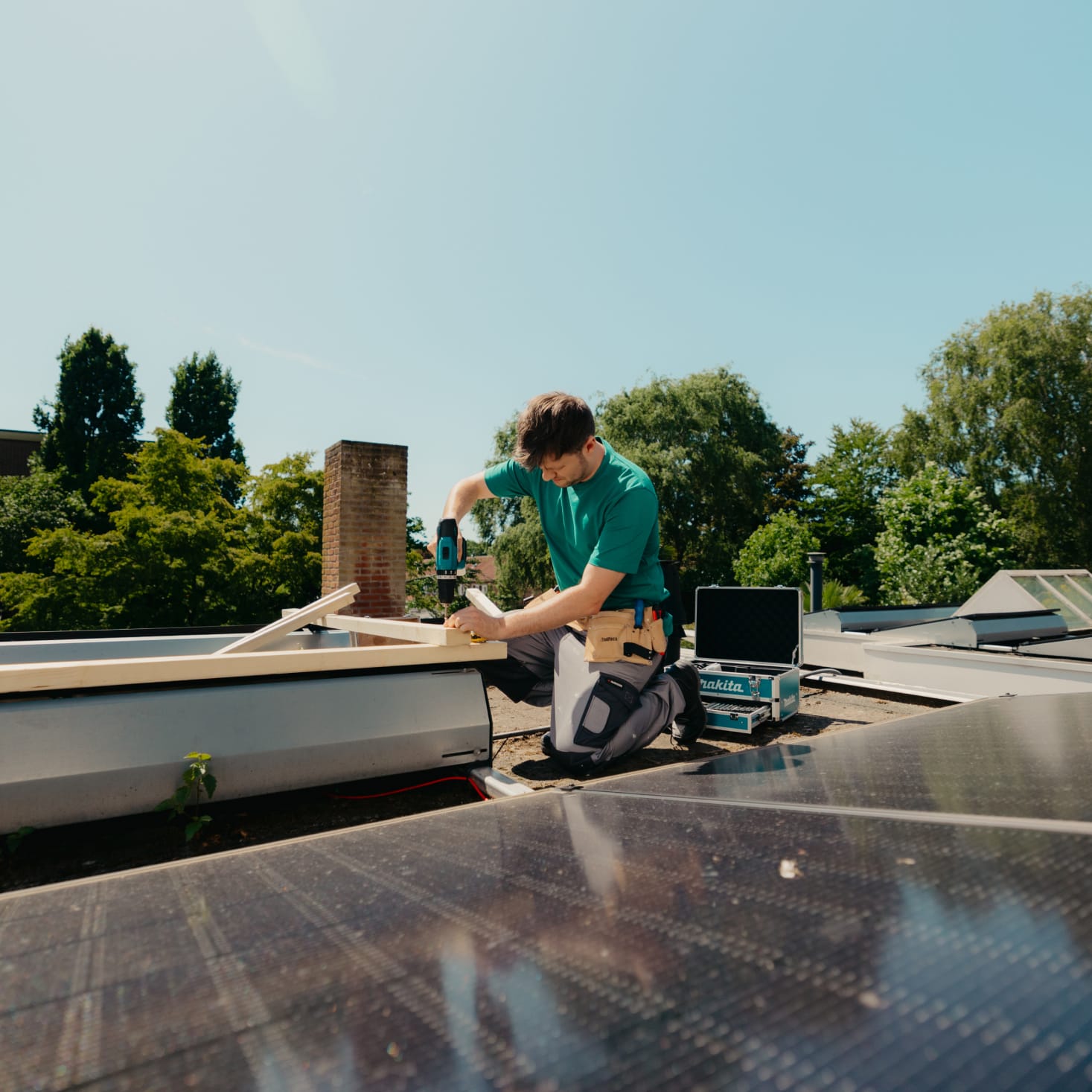 Arend met een boormachine in zijn hand aan het klussen op het dak van een woning