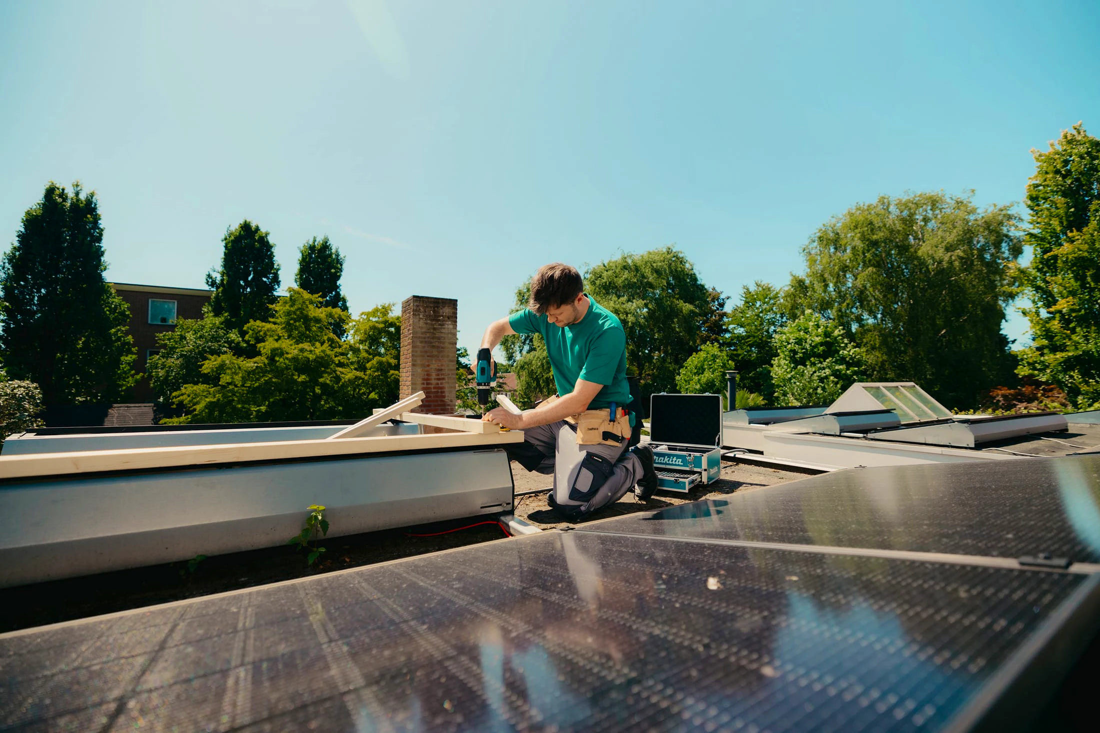 Arend met een boormachine in zijn hand aan het klussen op het dak van een woning