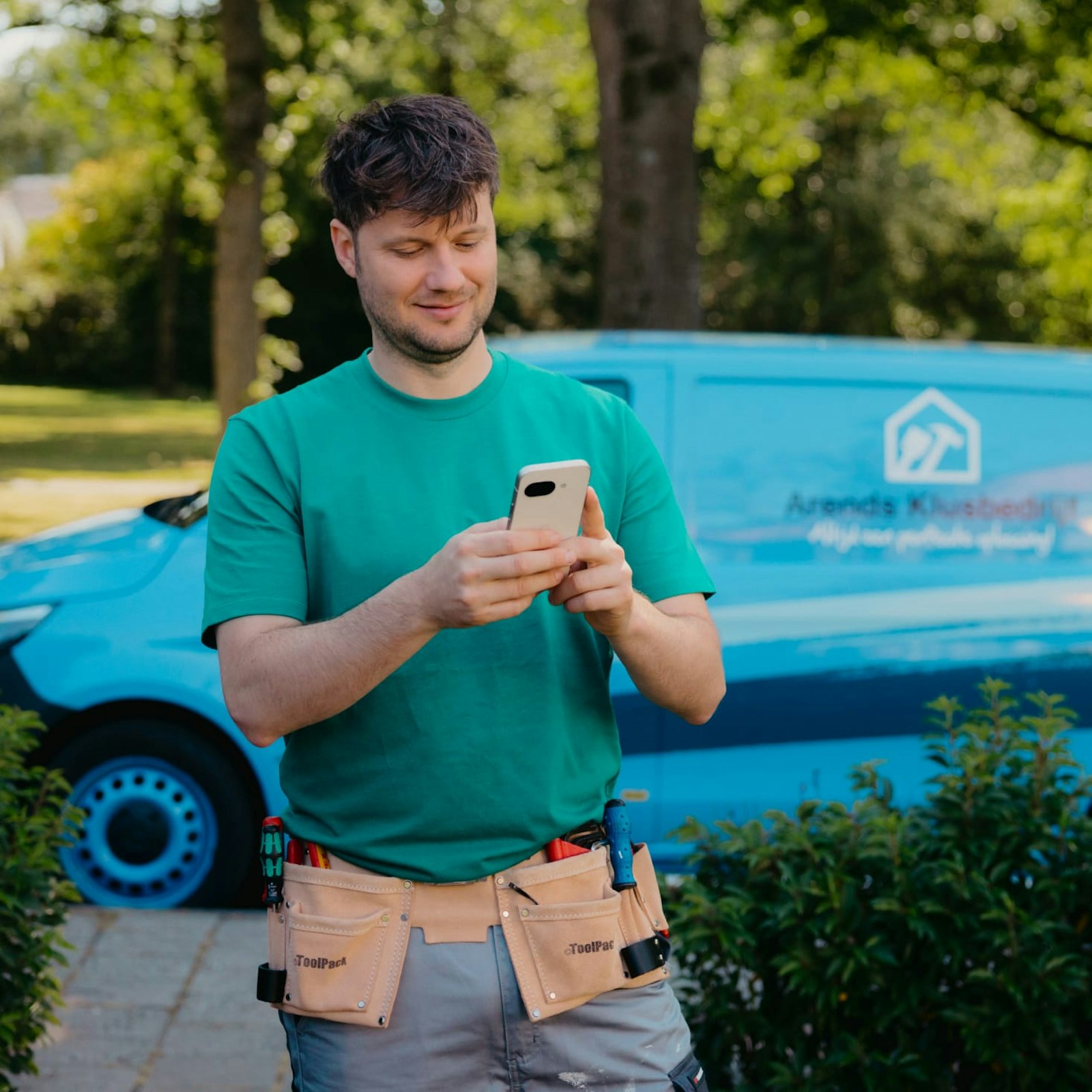 Arend met telefoon en zijn werkbus op de achtergrond