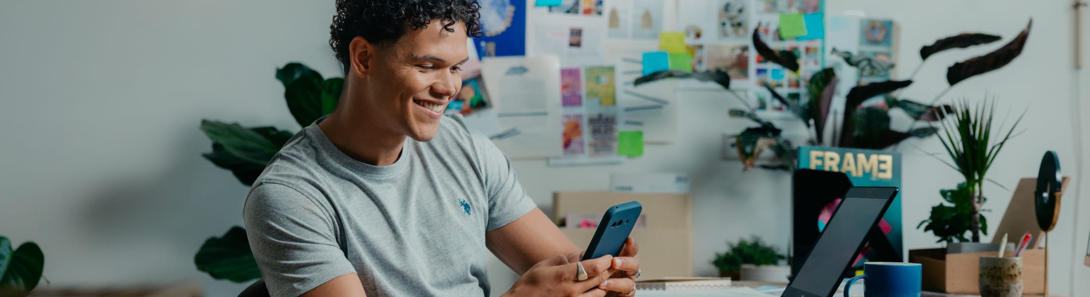 Mees met mobiel achter zijn bureau