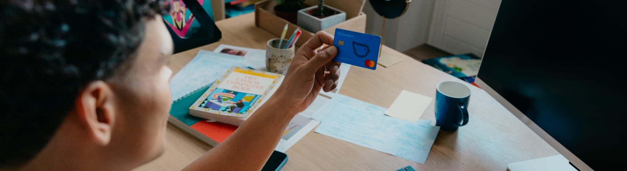 Mees met bankpas achter zijn bureau