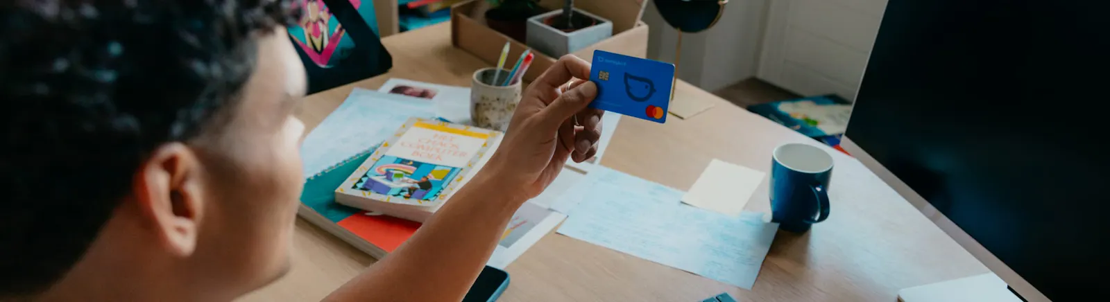 Mees met bankpas achter zijn bureau