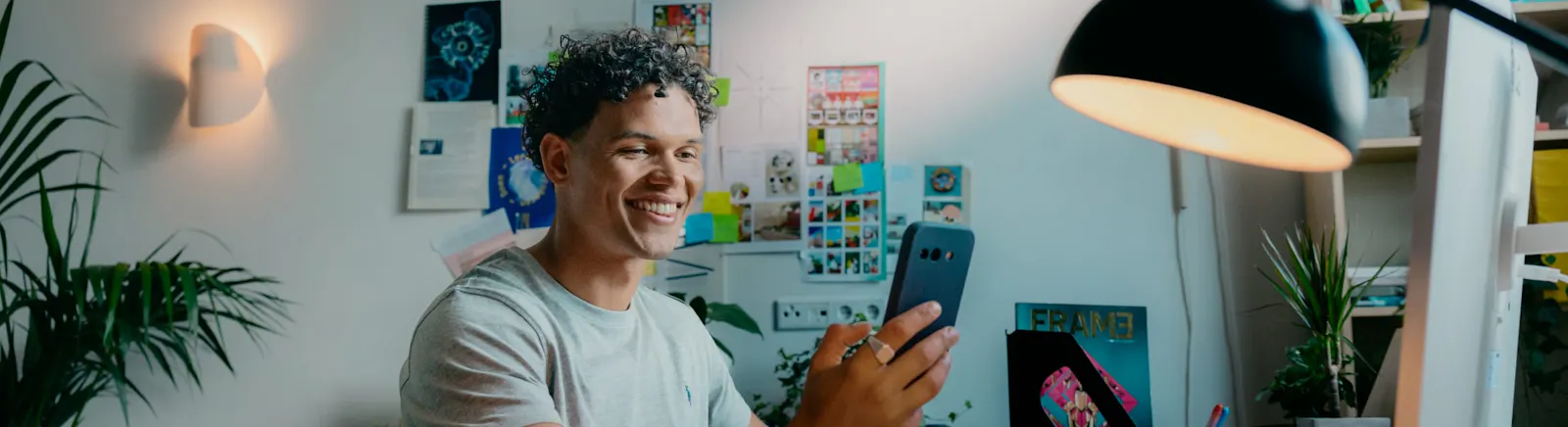 Mees met mobiel achter zijn bureau