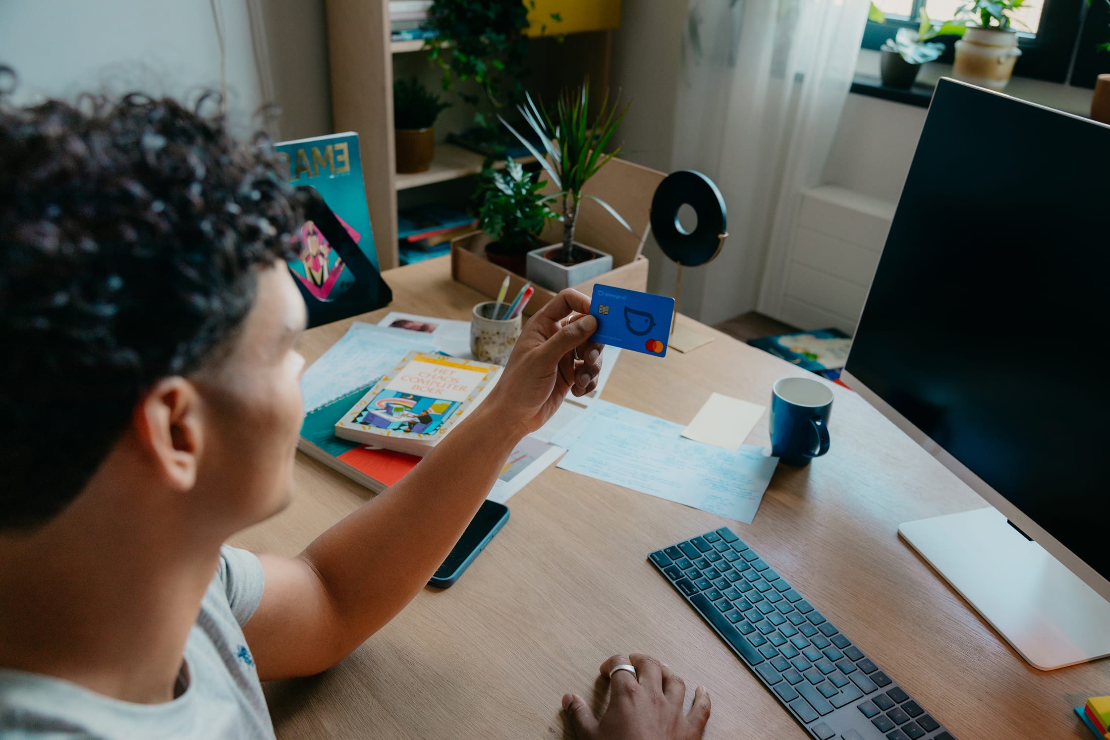 Mees met bankpas achter zijn bureau