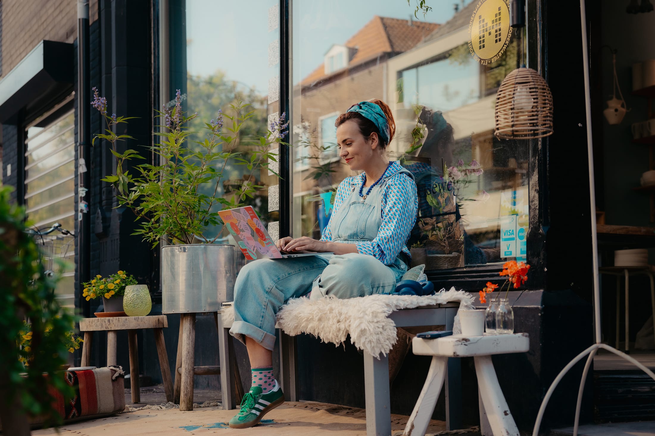 Merel met laptop buiten op een bankje voor haar winkel