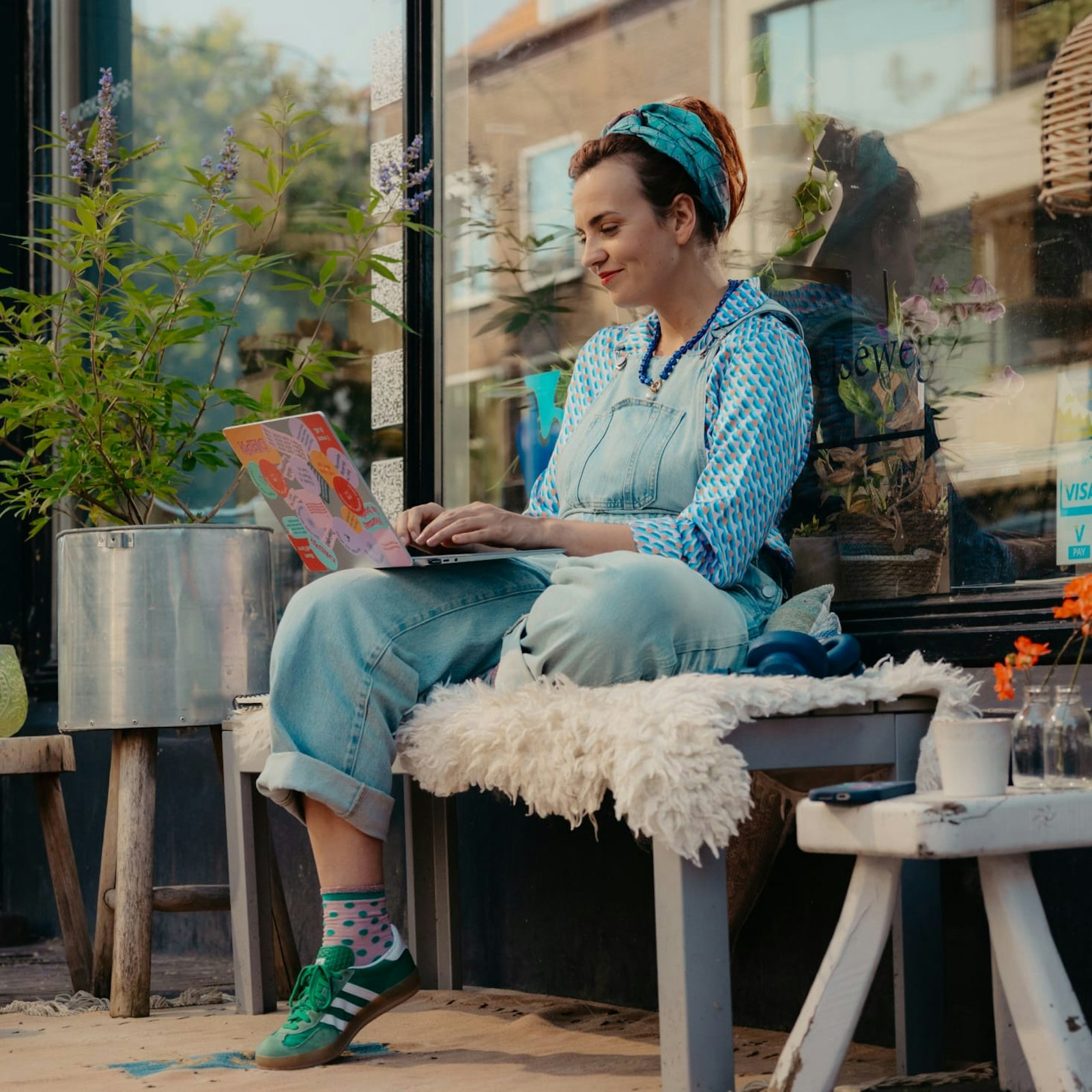 Merel met laptop buiten op een bankje voor haar winkel