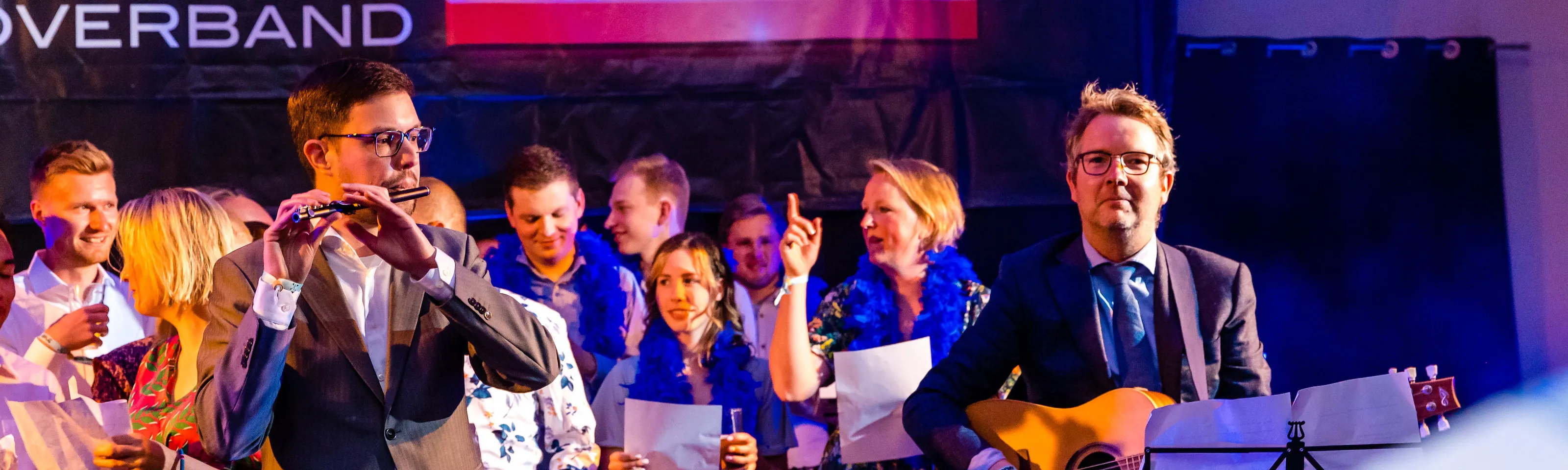 Edwin op de dwarsfluit en Joost op de gitaar met collega's op de achtergrond tijdens een bruiloft
