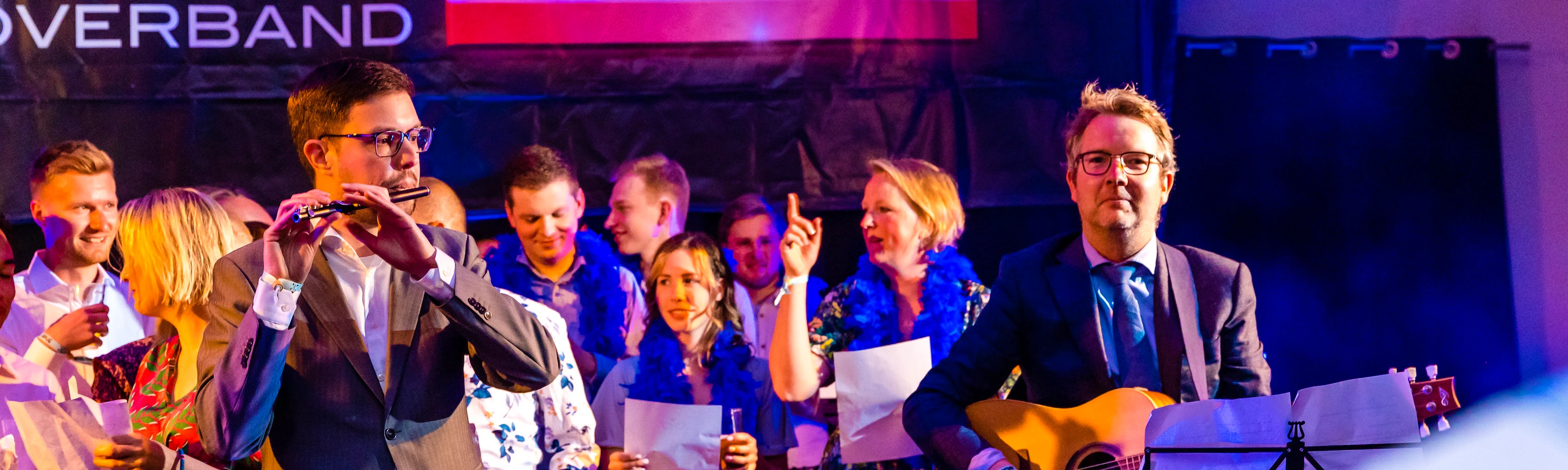 Edwin op de dwarsfluit en Joost op de gitaar met collega's op de achtergrond tijdens een bruiloft