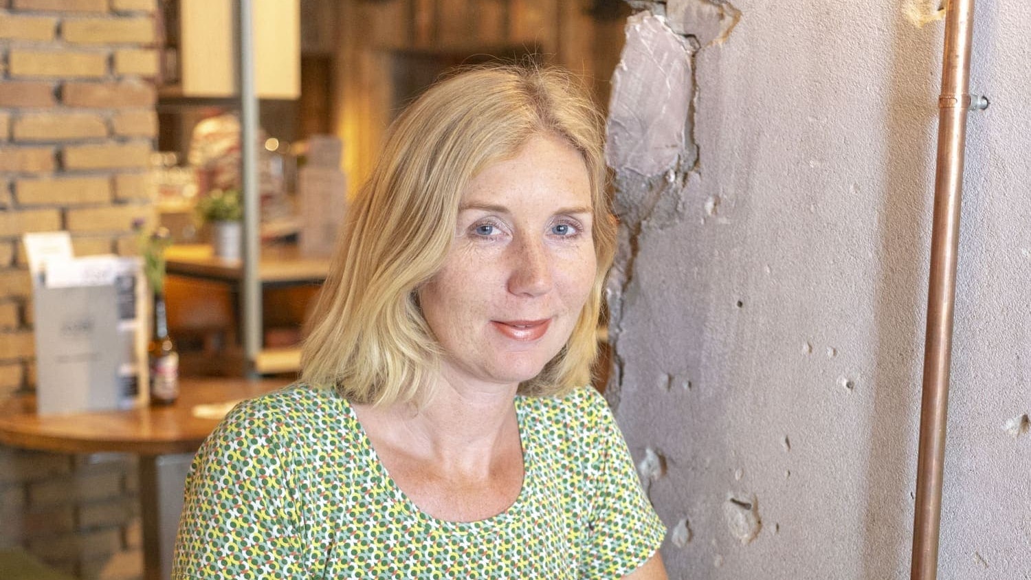 Annamarie kijkt in de camera en werkt achter haar laptop