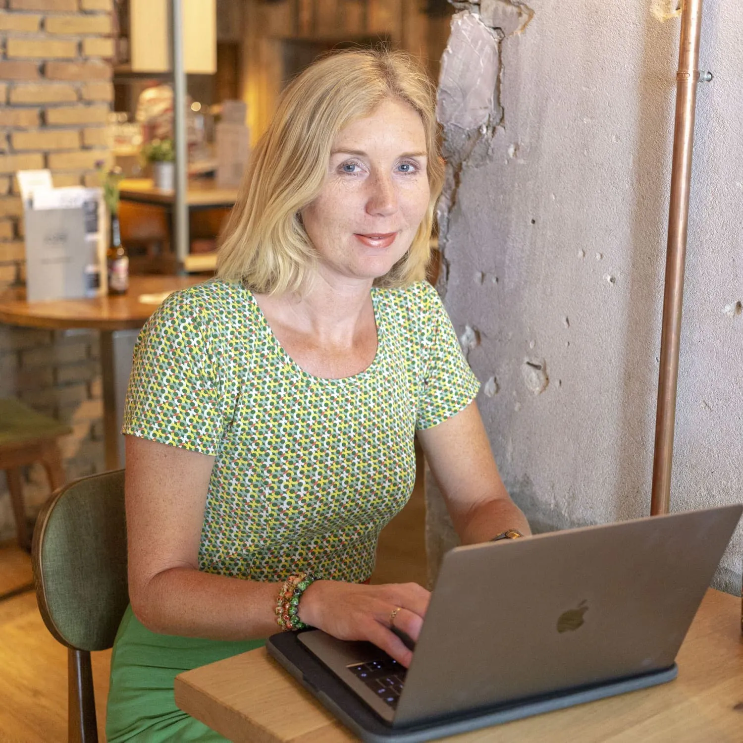Annamarie kijkt in de camera en werkt achter haar laptop