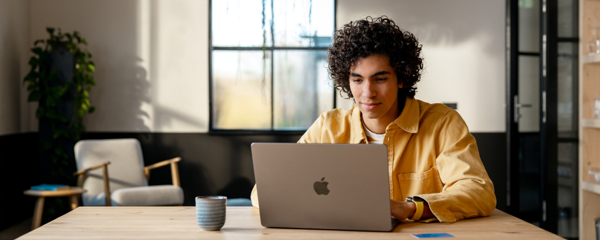 Ondernemer is aan het werk op zijn laptop aan een bureau. Geconcentreerd aan het werken in een geel vest.